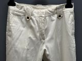 white pants hanging on a hanger against a gray wall
