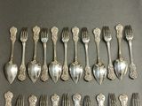 a lot of silver spoons and forks laid out on a table