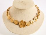 Collier avec une fleur en or présenté sur un mannequin devant un fond blanc