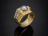 a gold ring with a diamond and baguets on a black surface