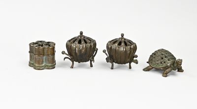 trois figurines en bronze représentant des tortues, disposées côte à côte sur une surface blanche