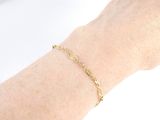 the hand of a woman is holding a gold chain bracelet