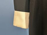 a close up of a black coat with a white collar and cuffs