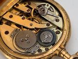 a close up of a pocket watch on a white surface