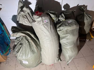 many bags of garbage sitting on the floor next to a wall