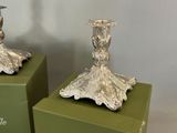 two silver candles that are sitting on a green box