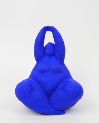 a close up of a blue sculpture of a person sitting on a white surface