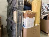 a pile of boxes and a mattress on a pallet in a warehouse