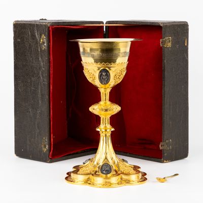 un calice ancien en or, dans un coffret en bois, posé sur une surface blanche