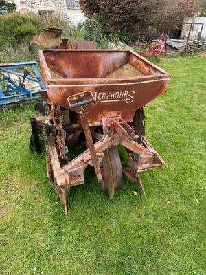 a rusted out old farm equipment in the grass