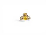 un gros plan d'une bague sertie d'un saphir jaune sur fond blanc