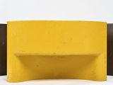 a yellow bench that is sitting on a white surface