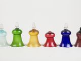 four different colored glass bottles are lined up on a white surface