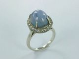 gros plan d'une bague avec une pierre bleue entourée de diamants
