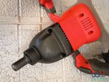 an overhead view of a red and black electric driller on a tiled floor