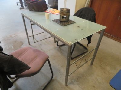 une table en verre avec deux chaises et un ordinateur portable posé dessus