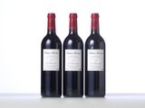 three bottles of red wine are lined up on a table