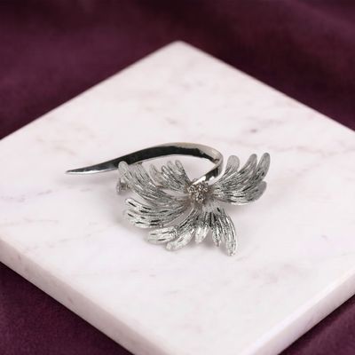 bague en forme d'oiseau en argent sterling plaqué, posée sur un bloc de marbre blanc