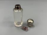 une petite bouteille en verre avec un bouchon en métal à côté