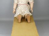 une vieille poupée assise sur une boîte portant le nom de « National Bébé Jumeal »