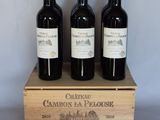 three bottles of red wine in a wooden crate on a table