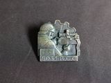 a close up of a metal pin with a picture of a man holding a gun