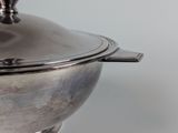 a silver bowl with a lid on a white table
