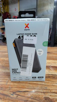 une photo d'un coffret contenant une batterie externe pour ordinateur portable, posé sur une table en bois