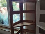 a corner shelf in the corner of a room next to a window