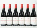 six bouteilles de vin rouge sont alignées sur une surface blanche