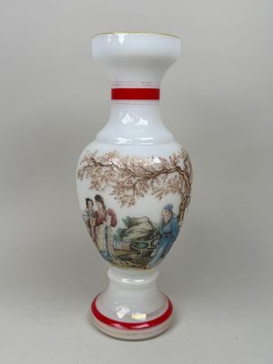 un vase blanc avec un tableau posé sur une table