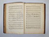 an open book with music notes on it sitting on a table