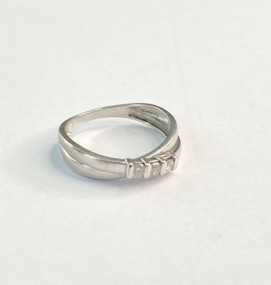 bague en argent ornée de trois pierres, posée sur une surface blanche