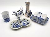 Plusieurs pièces de poterie bleue et blanche sont exposées sur un fond blanc