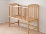 un lit bébé dans une chambre avec une fenêtre et un parquet