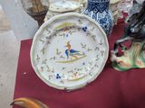 a plate with a bird on it sitting on a table next to a vase