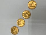 quatre pièces d'or sont disposées en ligne sur une surface blanche