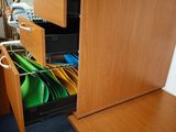 une armoire en bois avec un tiroir rempli d'objets verts et jaunes