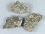 trois morceaux de roche verte posés sur une surface blanche