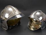 pair of silver helmets on a black surface with a black background
