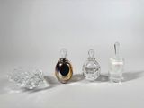 trois flacons de parfum en verre posés les uns à côté des autres sur une surface blanche