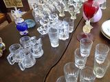 many glasses on a table with a vase on it