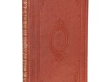 un vieux livre à la couverture rouge posé sur une surface blanche