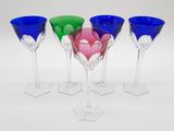 quatre verres à vin de couleurs différentes posés les uns à côté des autres sur une surface blanche