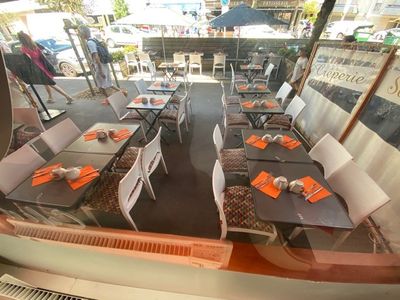 many tables and chairs in a restaurant with orange napkins