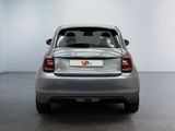 the back end of a silver car in a room with a white wall
