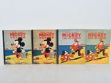 three mickey mouse books sitting on top of a white table