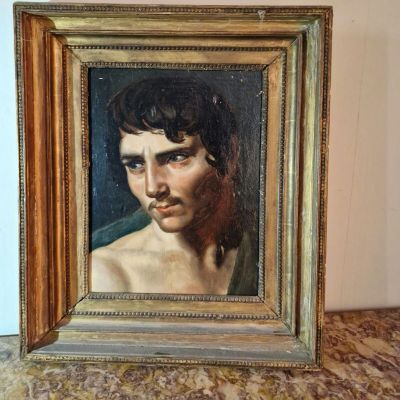 painting of a young man in a gold frame on a table