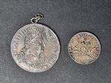 une vieille pièce d'argent et une pièce d'argent posée sur une surface noire