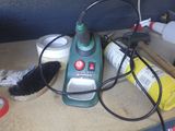 un aspirateur vert et noir posé sur un plan de travail, muni d'une brosse